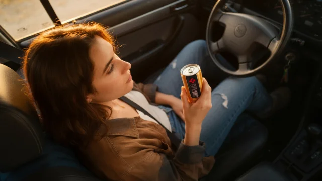 A driver holding a JavaPlus can in the car