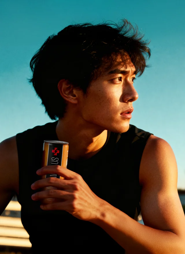 A young man holding a JavaPlus can