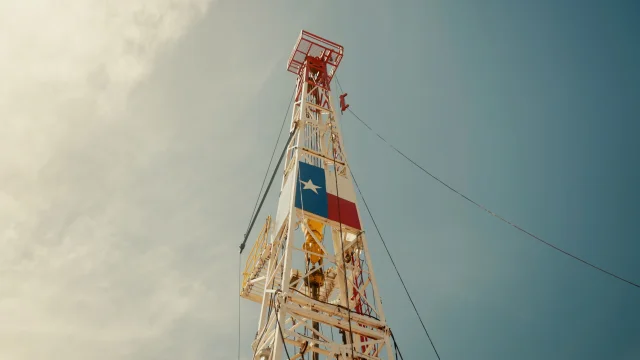 A Pure Oil & Gas drilling rig flying the Texas flag against an open sky
