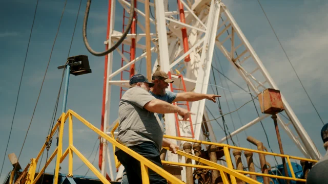 Two crew members on a Pure Oil rig platform, one pointing across the site